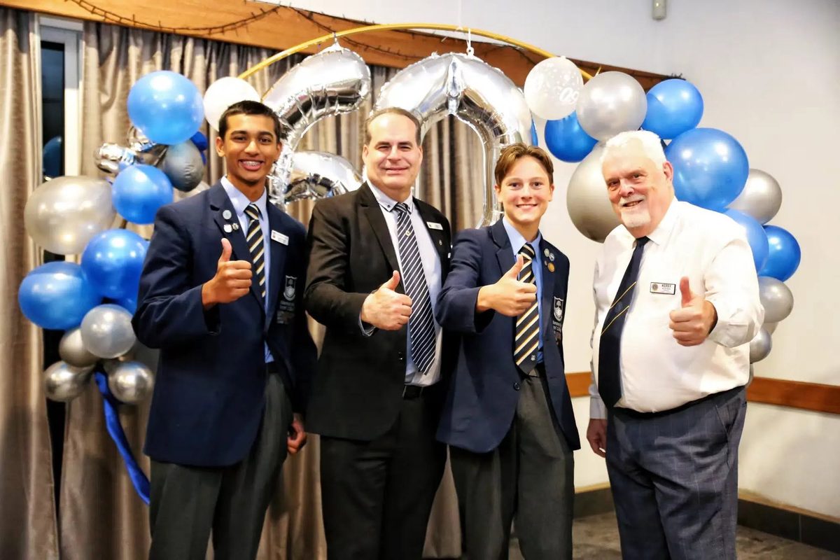 Members and students giving a thumbs-up in front of silver 60 balloons at the Lions Club of Brisbane Camp Hill Carindale 60th anniversary dinner