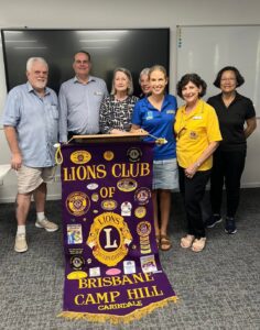Members of the Lions Club of Brisbane Camp Hill Carindale with the club banner