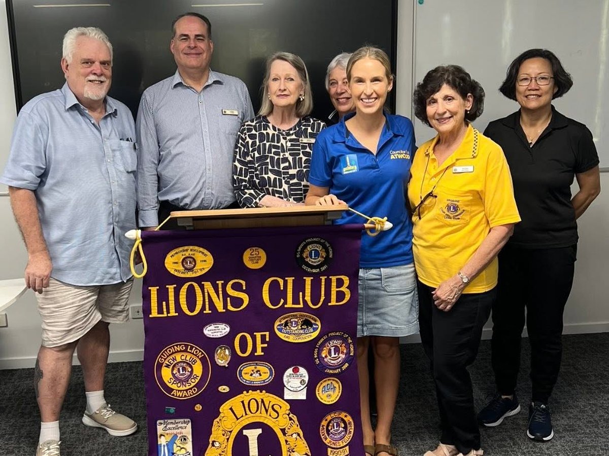Members of the Lions Club of Brisbane Camp Hill Carindale with the club banner