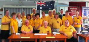 Members of the Lions Club of Brisbane Camp Hill Carindale gathered around a meeting table.”