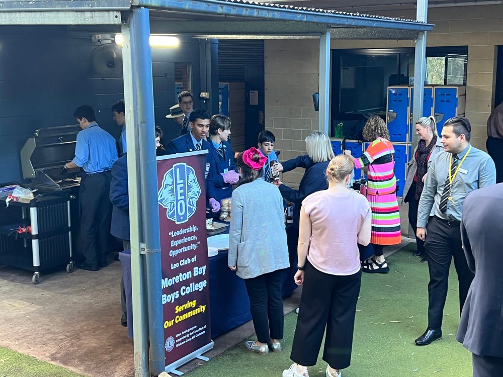 Leo Club students serving a barbecue breakfast beside the Moreton Bay Boys’ College Leo Club banner